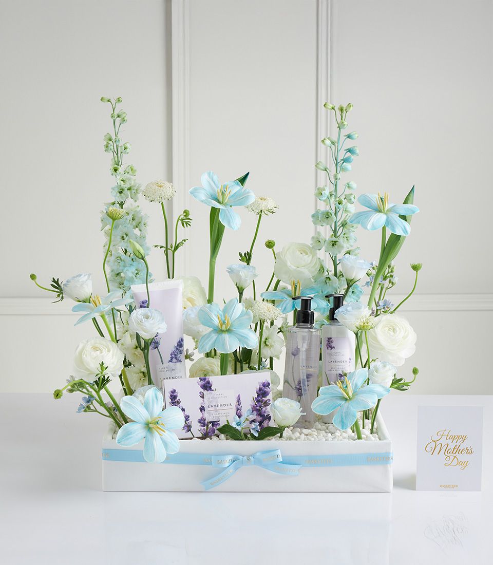 Luxury lavender spa basket with bath products, white ranunculus, and delphiniums for Mother's Day