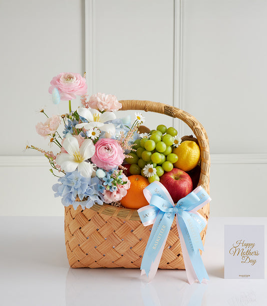 Pastel Mother's Day fruit basket with pink ranunculus, hydrangeas, fresh citrus and grapes in woven wicker