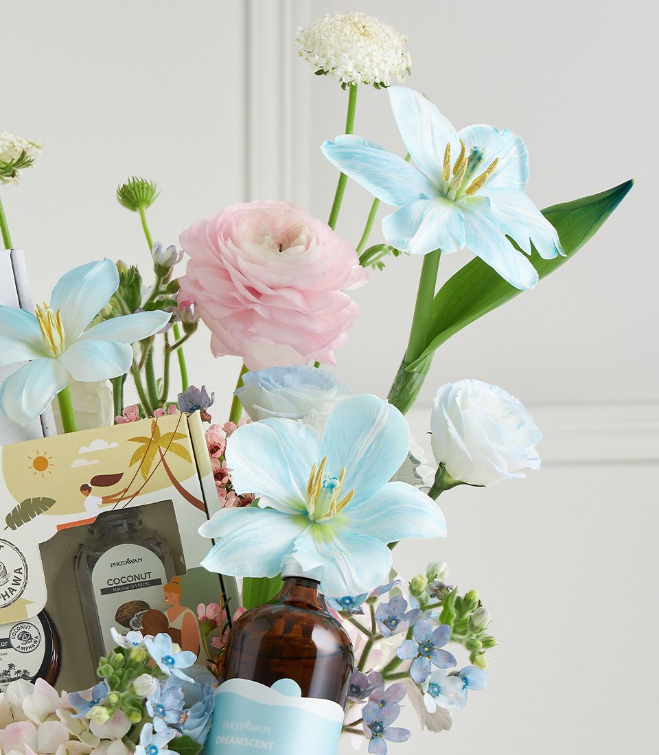 Pastel Mother's Day spa gift box with blue tulips, pink ranunculus, coconut oil, and aromatherapy products in floral