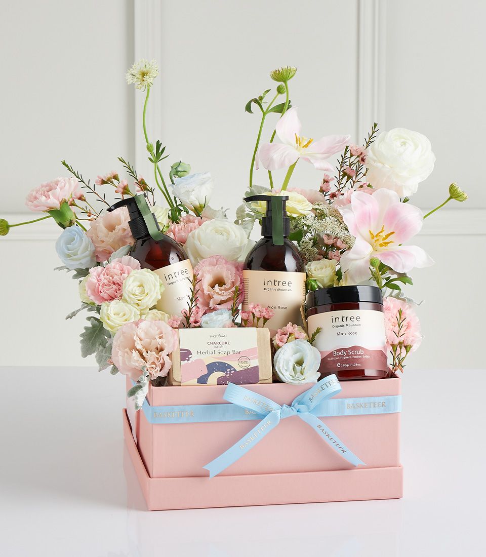 Basketeer luxury gift basket Bangkok: Spa gift box with soaps, lotions and body scrub nestled among fresh pastel flowers. Light blue ribbon.