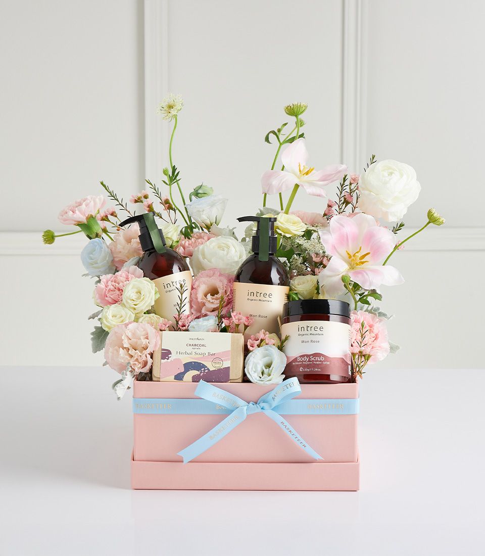 Basketeer premium spa gift in pink box, a luxury gift basket Bangkok. Includes floral bouquet, body scrub, and bath products, finished with a light blue ribbon.