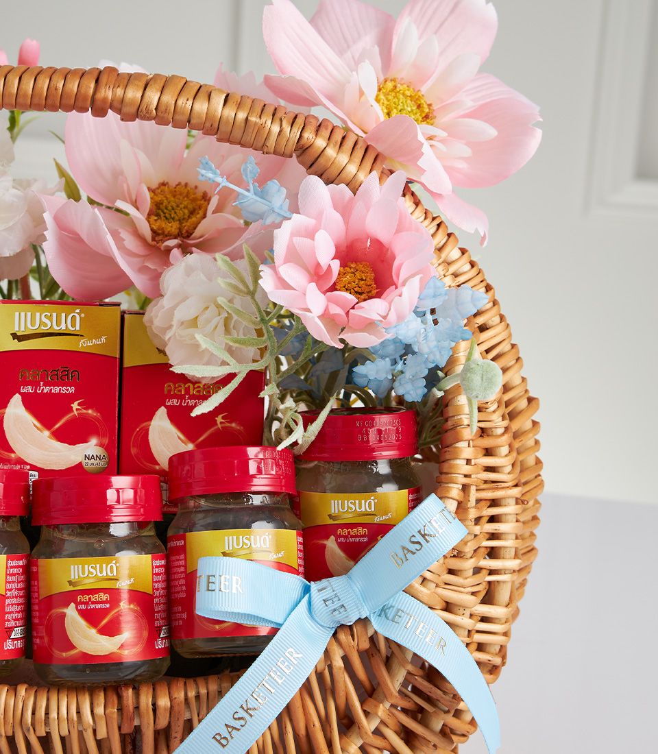 Woven wicker Mother's Day gift basket with bird's nest jars, red boxes, and pink artificial flowers with light blue ribbon