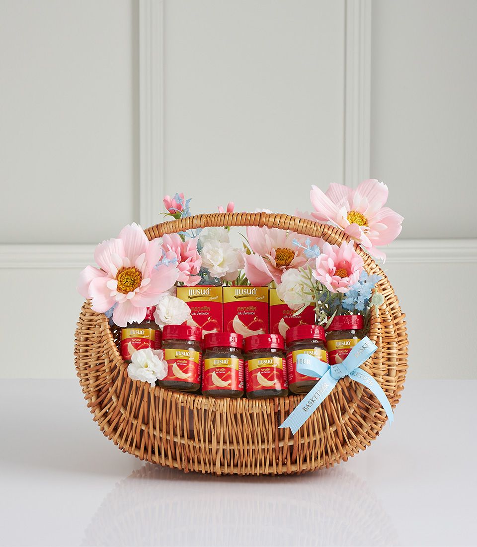 Classic bird's nest gift basket with wicker weave, red-capped jars, and pink-white-blue artificial flowers for Mother's Day