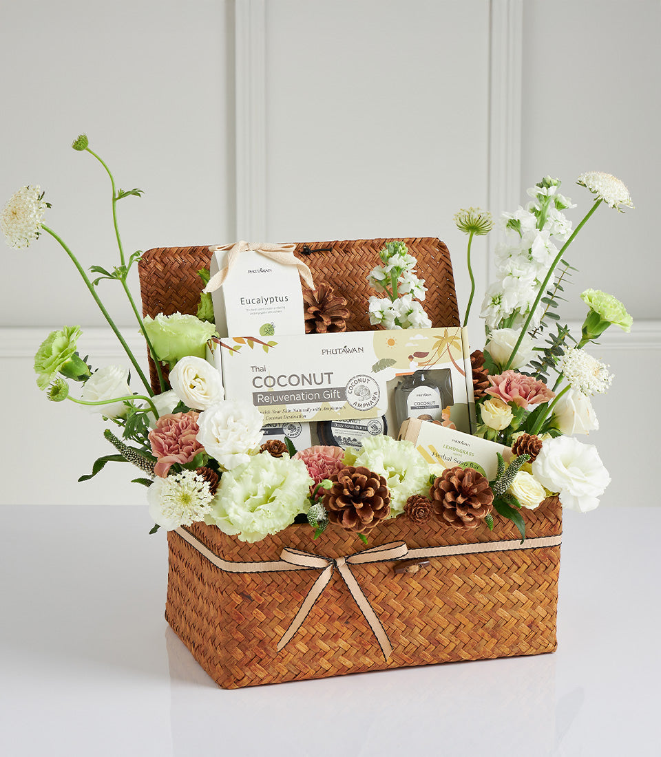 Woven spa gift basket with eucalyptus, coconut rejuvenation, and lemongrass soap, adorned with fresh white and pink flowers
