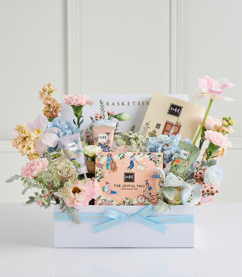 Luxe Mother's Day gift hamper with hand cream set, fragrant tubes, and fresh pastel flowers in premium white box