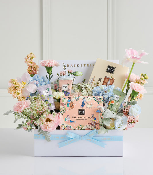 Luxe Mother's Day gift hamper with hand cream set, fragrant tubes, and fresh pastel flowers in premium white box