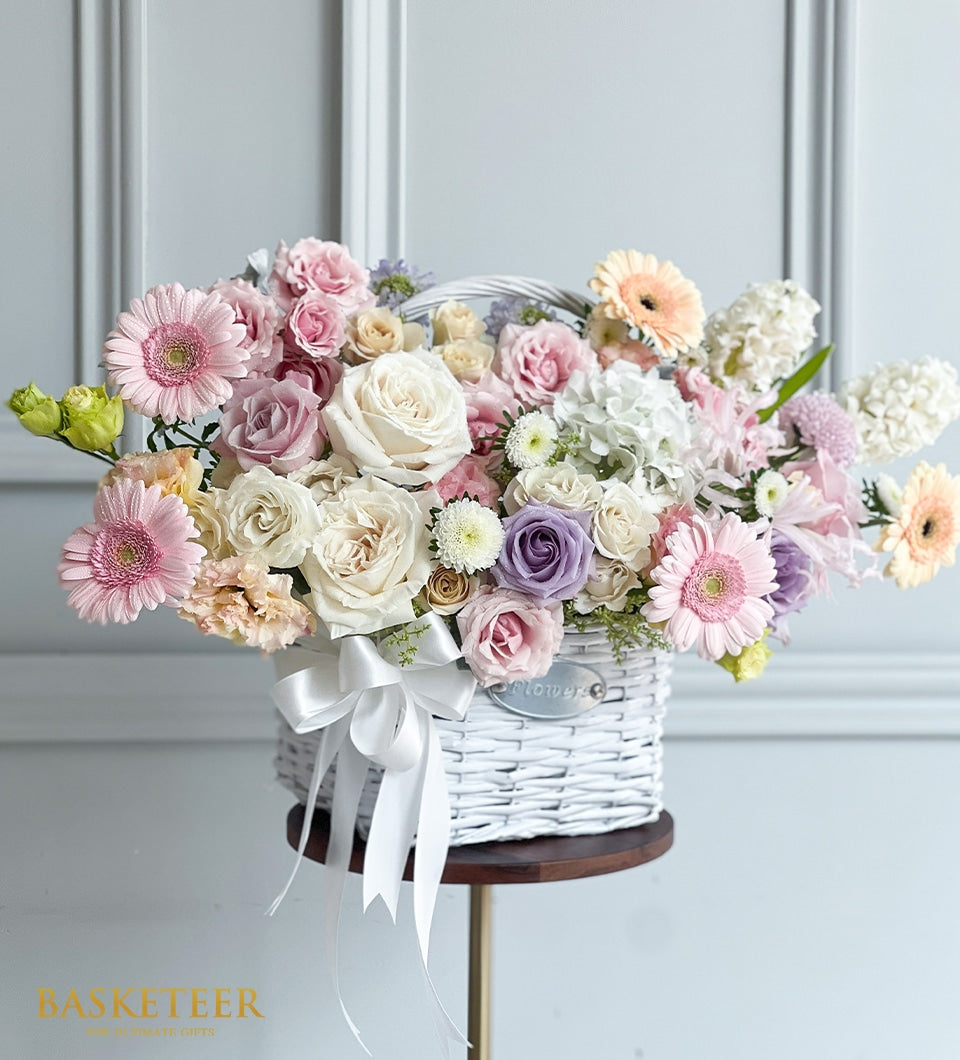 Soft pastel rose and hydrangea arrangement in white woven basket with satin ribbon, premium fresh flowers for birthdays and