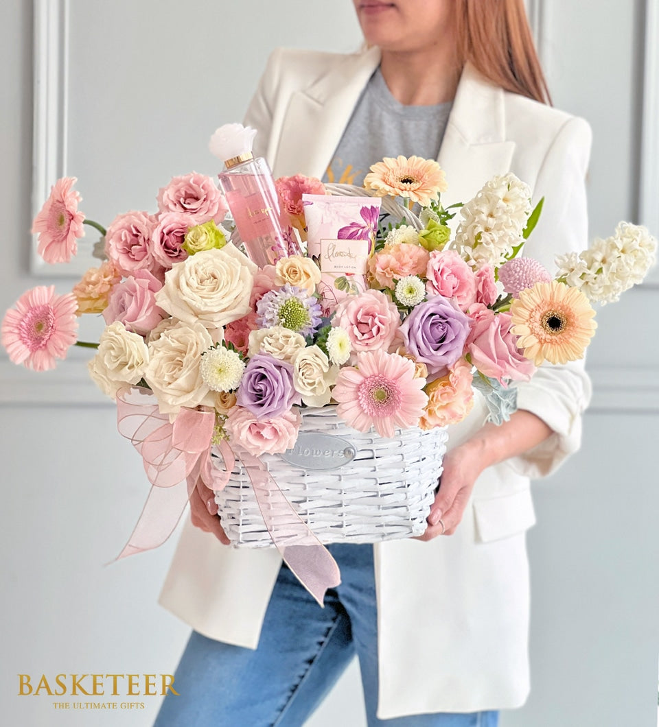 White woven Mother's Day basket with cream and blush roses, gerbera daisies, hyacinths, pink perfume and body lotion with