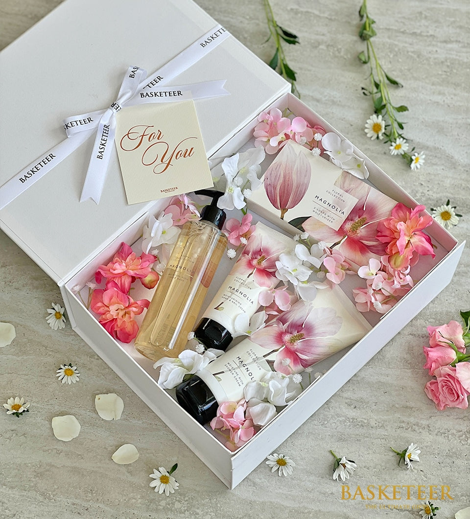 Luxe spa gift set with magnolia bath products, hand cream, and soap in white gift box with floral accents for Mother's Day