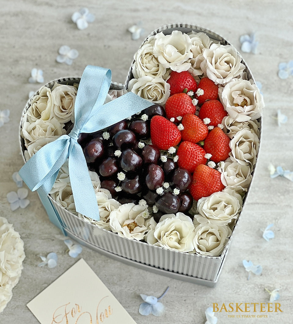 Heart-shaped silver gift box with fresh strawberries, cherries, and premium white roses for birthdays and celebrations