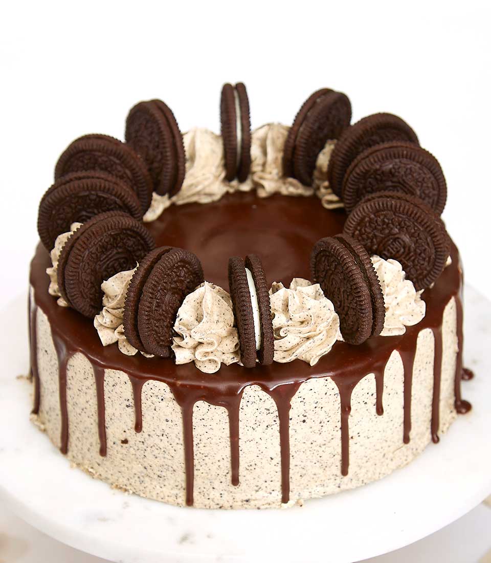 Oreo-chocolate cream layer cake with crushed cookie buttercream and chocolate ganache drip, topped with whole Oreos