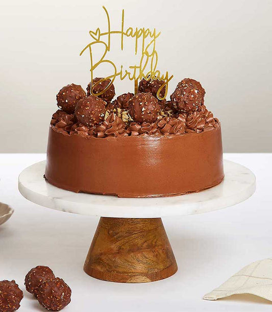Ferrero Rocher chocolate birthday cake with piped rosettes and gold topper on marble stand