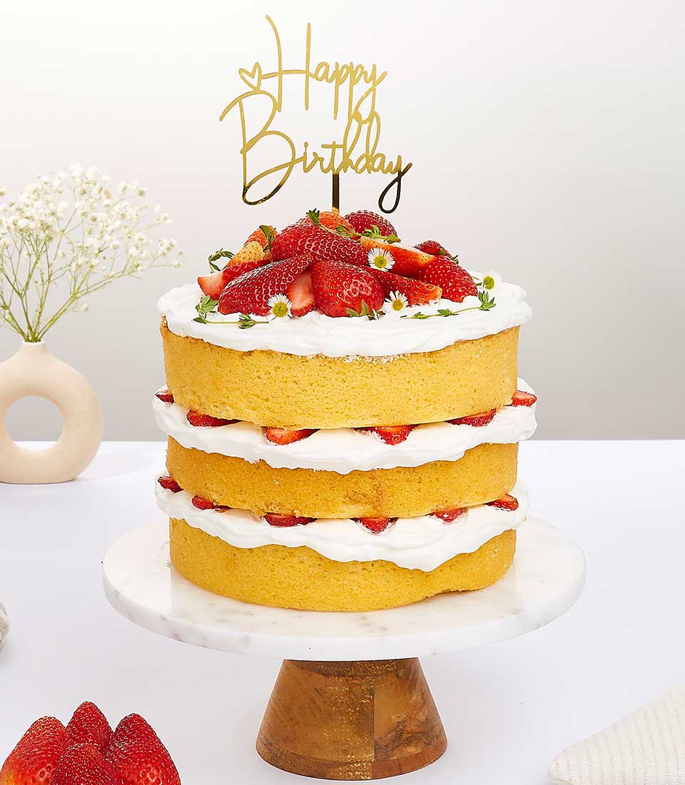 Elegant three-tier strawberry shortcake with fresh berries and whipped cream on marble stand, adorned with Happy Birthday