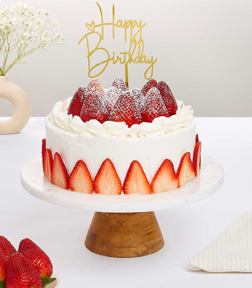 Strawberry vanilla chiffon birthday cake with fresh strawberries and white cream frosting on marble stand