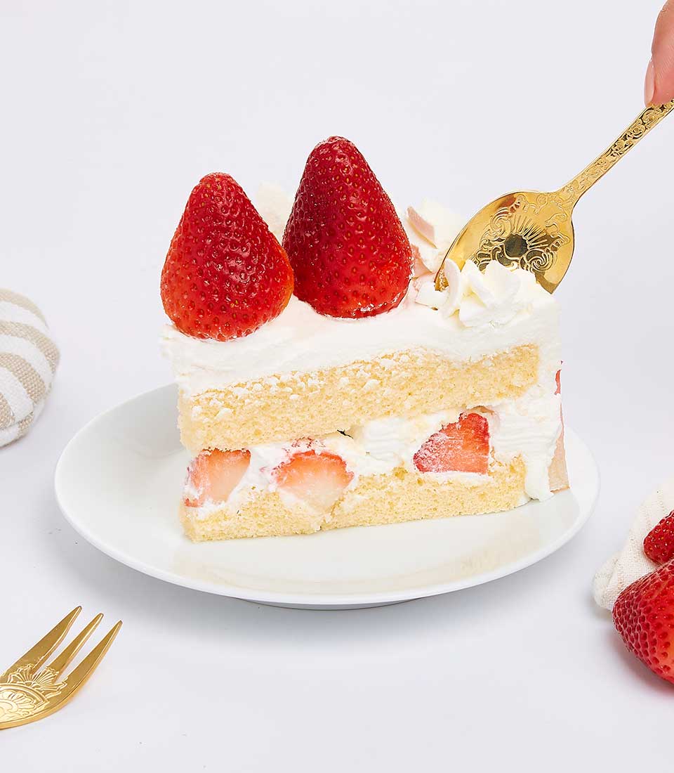 Light strawberry vanilla chiffon cake with whipped cream and fresh berries, served on white ceramic plate