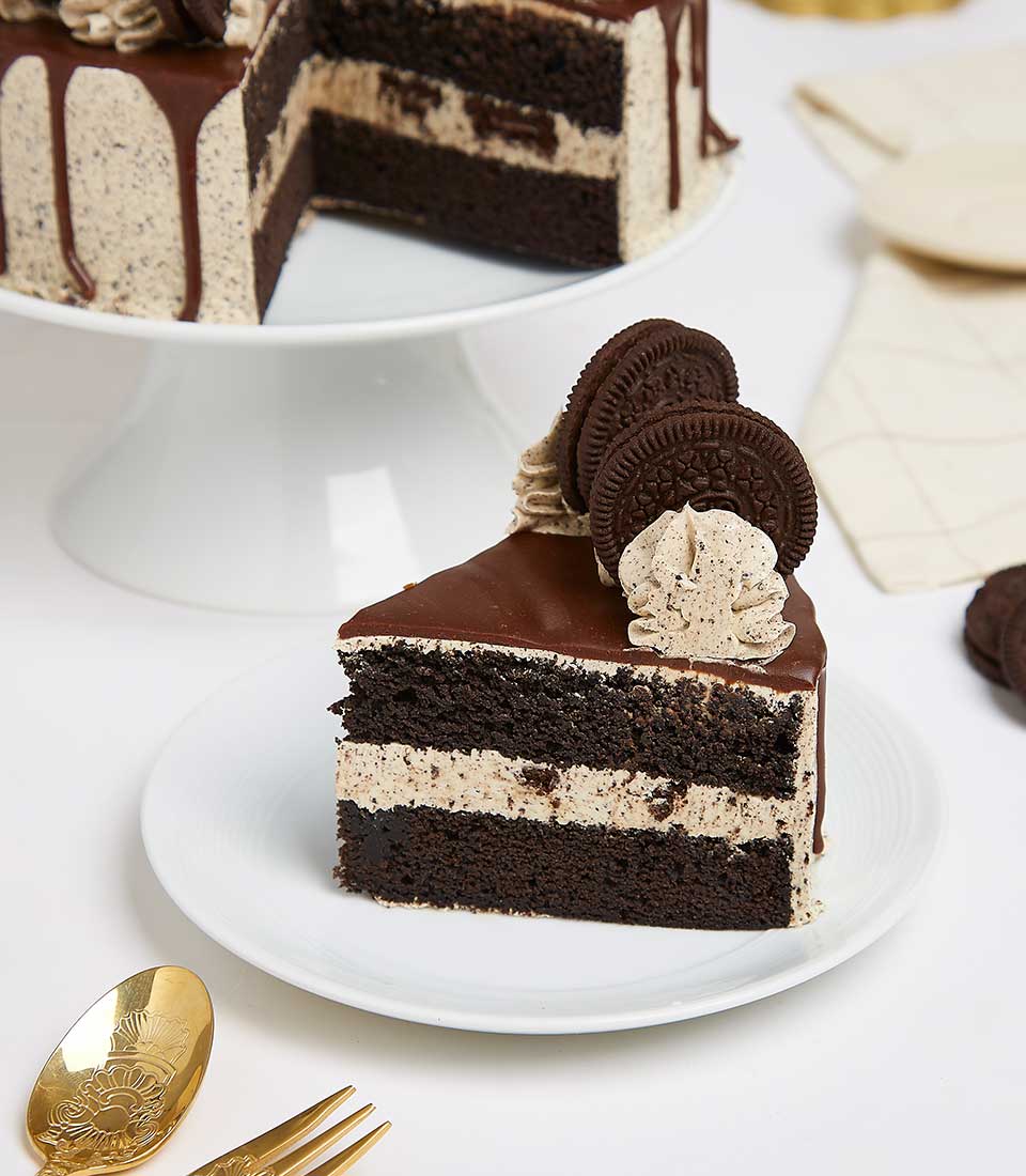 Oreo-chocolate cream layer cake slice with dark ganache and cookie crumble garnish