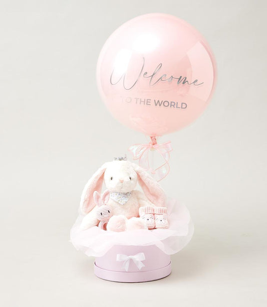 Luxury pink and white baby welcome hamper with plush bunny, crocheted toy, knitted booties, and welcome balloon in hat box