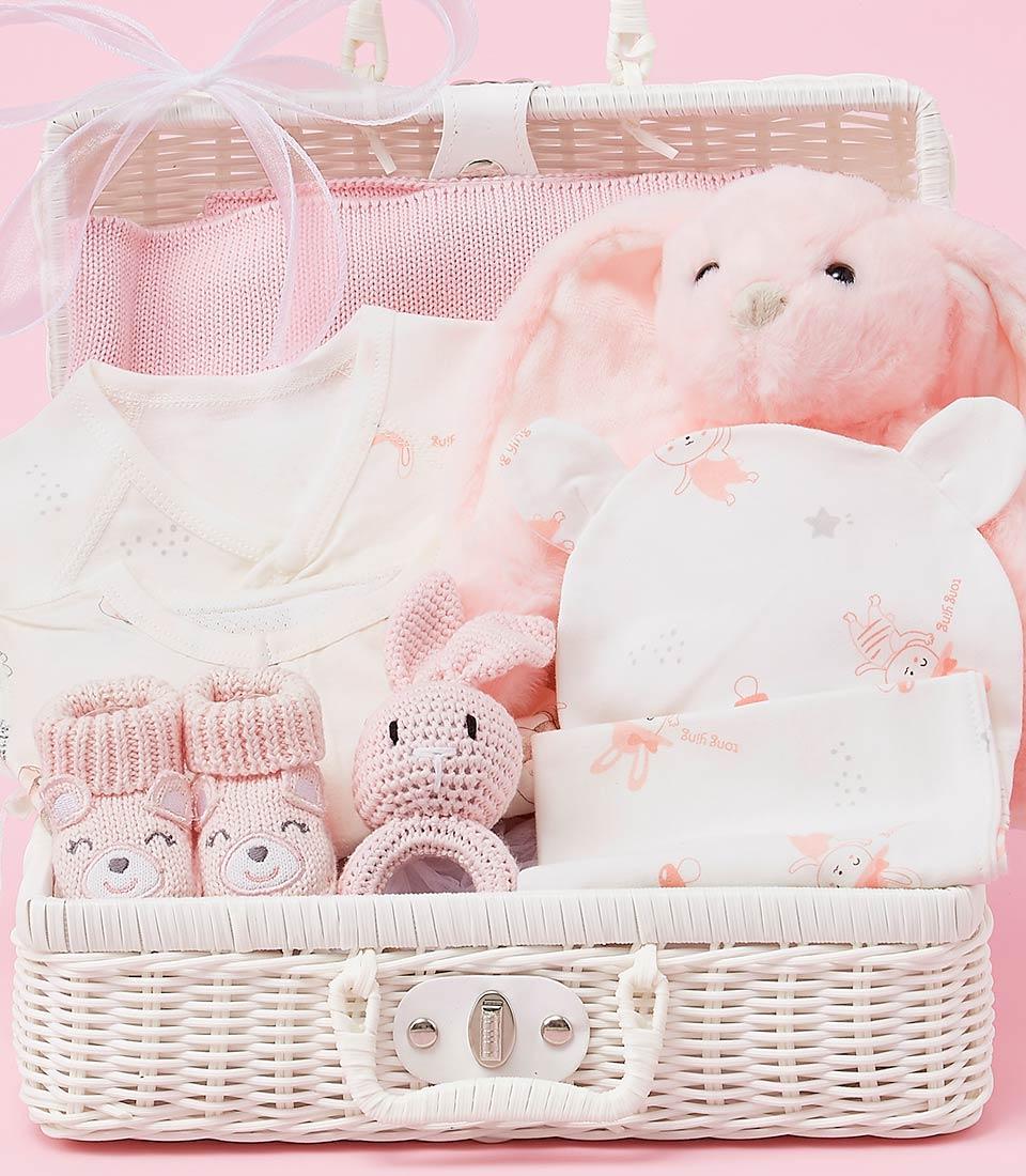 Luxury pink and white baby girl gift basket with plush bunny, knitted blanket, onesie, and booties