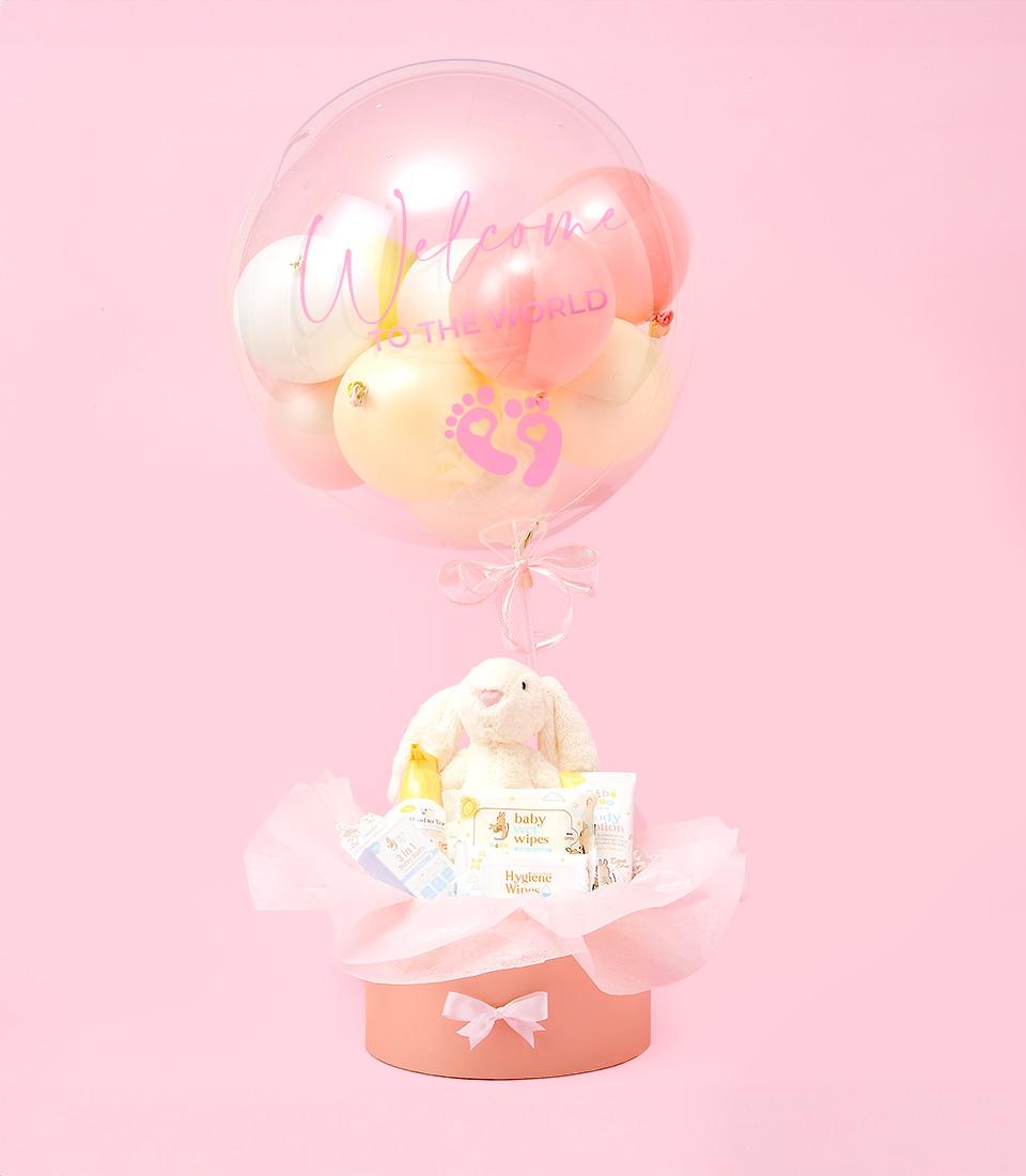 Pastel hot air balloon newborn gift set with plush bunny, baby wipes, and welcome message in peach keepsake box