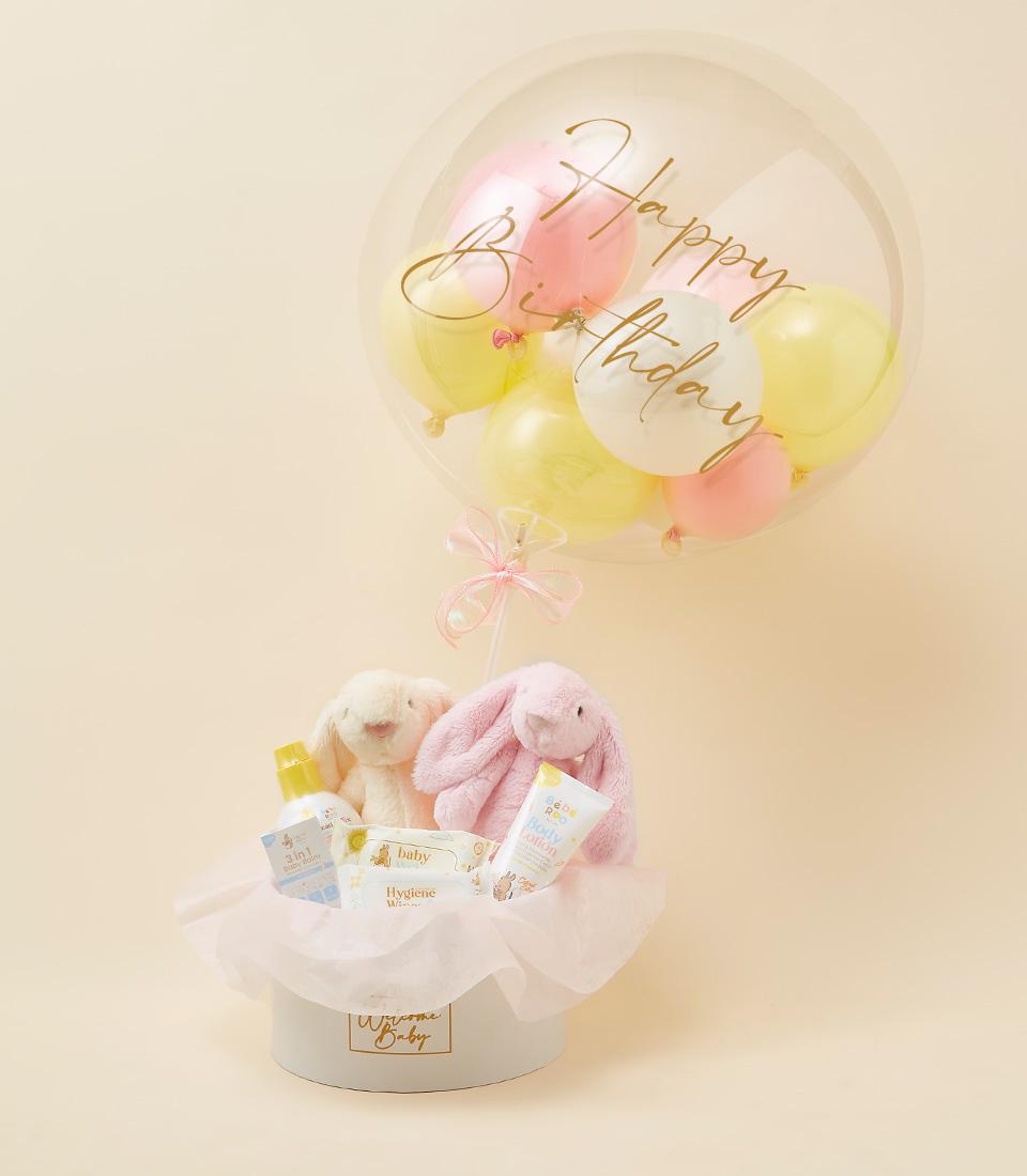 Luxury newborn gift set with plush bunnies, baby wash, wipes, and lotion in soft pink and cream