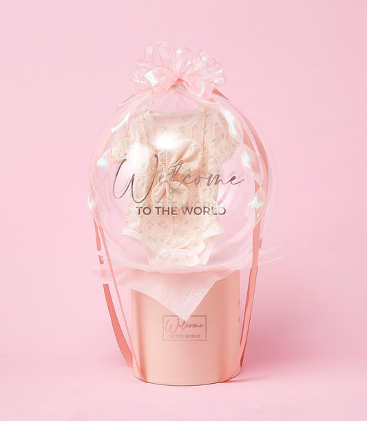 Newborn gift set with baby romper inside clear balloon tied with pink ribbon bow, Welcome to the World message