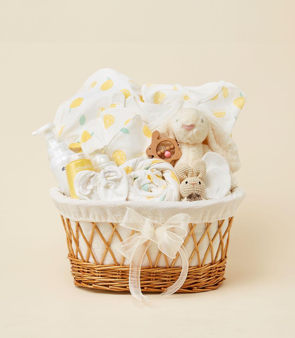 Lemon Sunshine newborn gift basket with yellow patterned baby clothing, cream bunny plush, and essentials in woven wicker