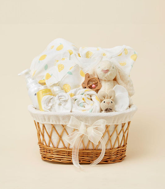 Lemon Sunshine newborn gift basket with yellow patterned baby clothing, cream bunny plush, and essentials in woven wicker