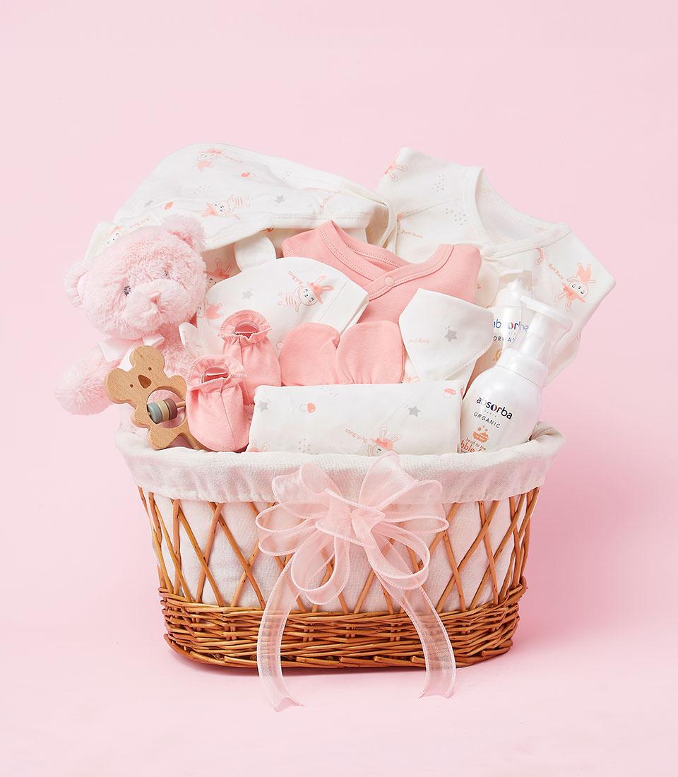 Hello Baby Girl Bliss newborn gift basket with pink teddy bear, organic baby products, and soft clothing in woven wicker