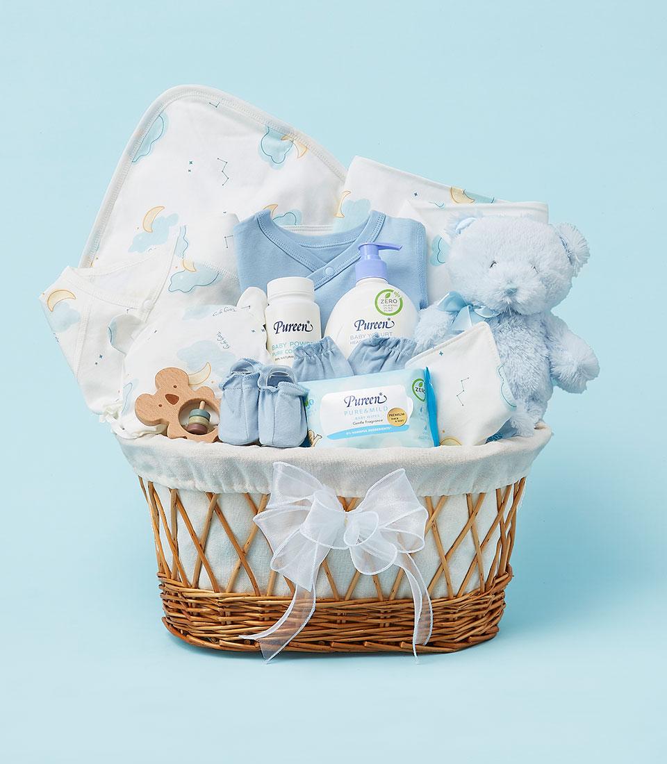 Blue and white newborn gift basket with onesie, cloud blanket, booties, teddy bear, and baby care essentials