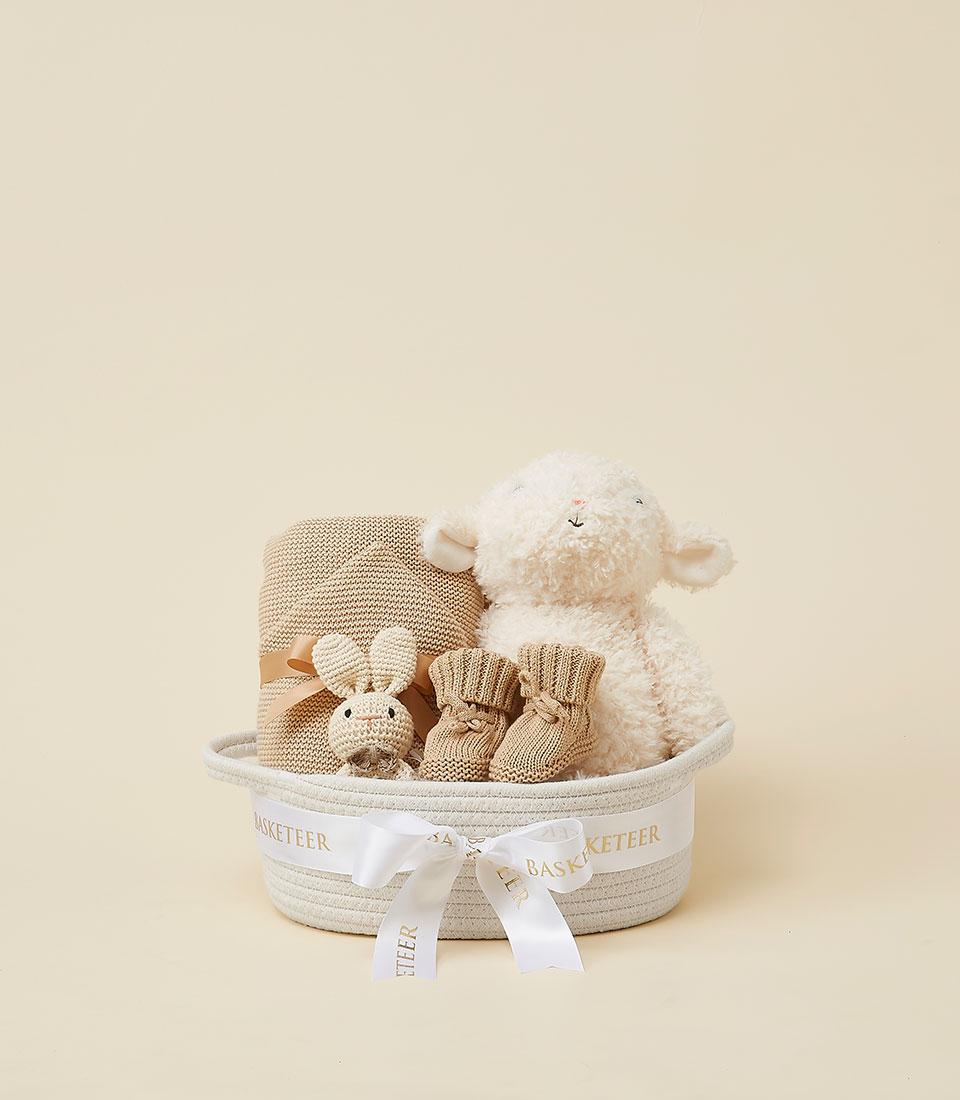 Cozy neutral baby gift basket with crocheted bunny, knitted booties, and soft lamb plush