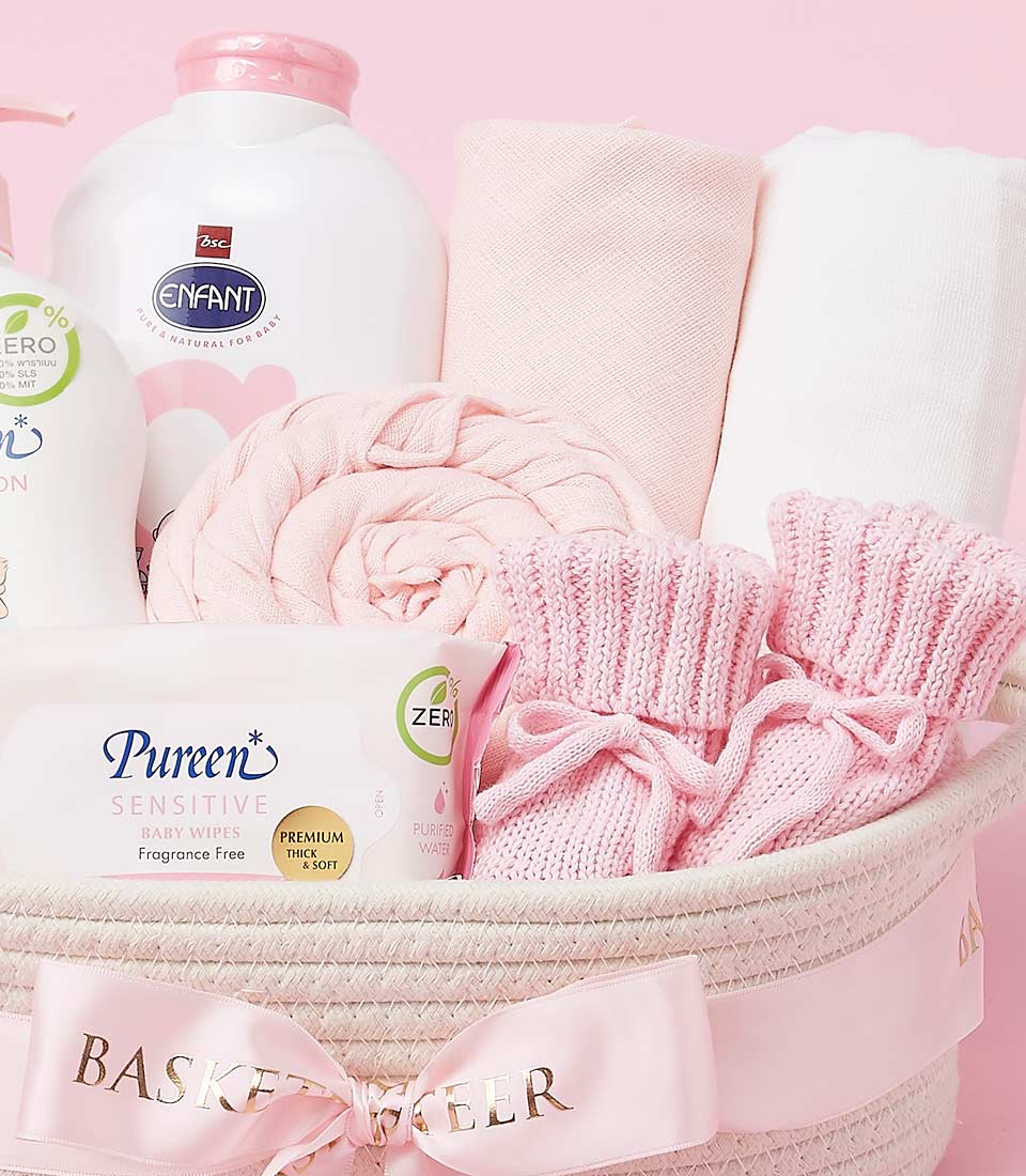Deluxe pink and white baby care gift basket with knitted blanket, bottles, wipes, and booties