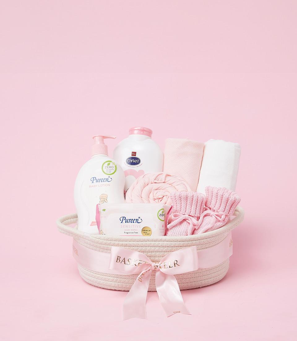 Deluxe baby care hamper with lotion, wipes, booties and blanket in woven basket with pink ribbon