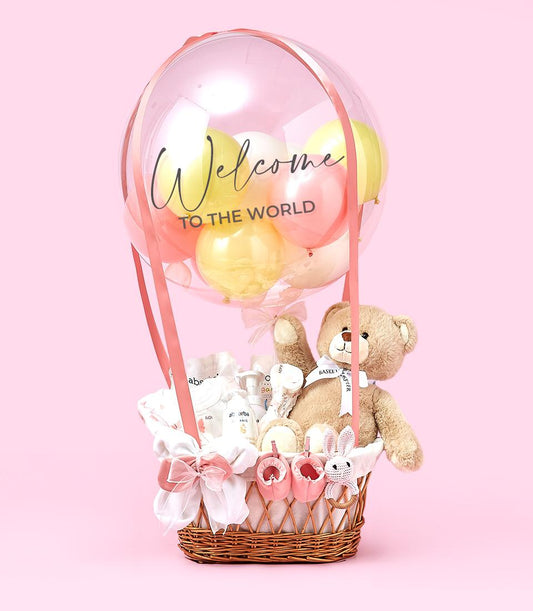 Luxury hot air balloon newborn gift hamper with clear balloon sphere, pink ribbons, wicker basket, baby clothing, booties,