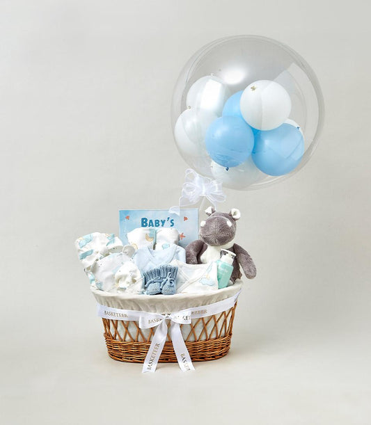Limelight Baby wicker gift basket with light blue onesie, booties, plush hippo toy, and balloon arrangement