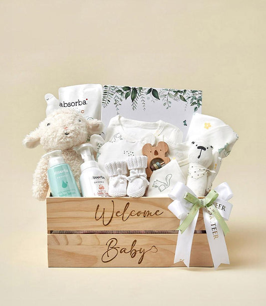 Wooden crate newborn gift set with plush lamb toy, baby care products, white onesie, knitted booties, and wooden teether