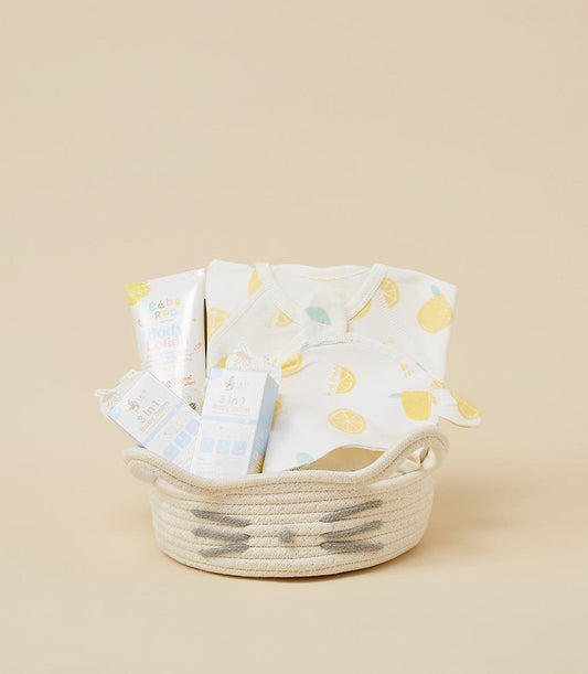 Woven cat-face baby gift basket with lemon-print bodysuit, bib, and skincare set for newborns
