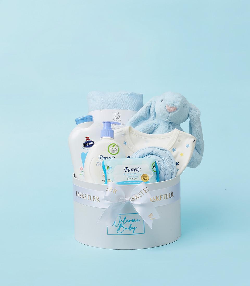 Gentle white hatbox baby welcome gift with plush bunny, star bib, blanket, and care products