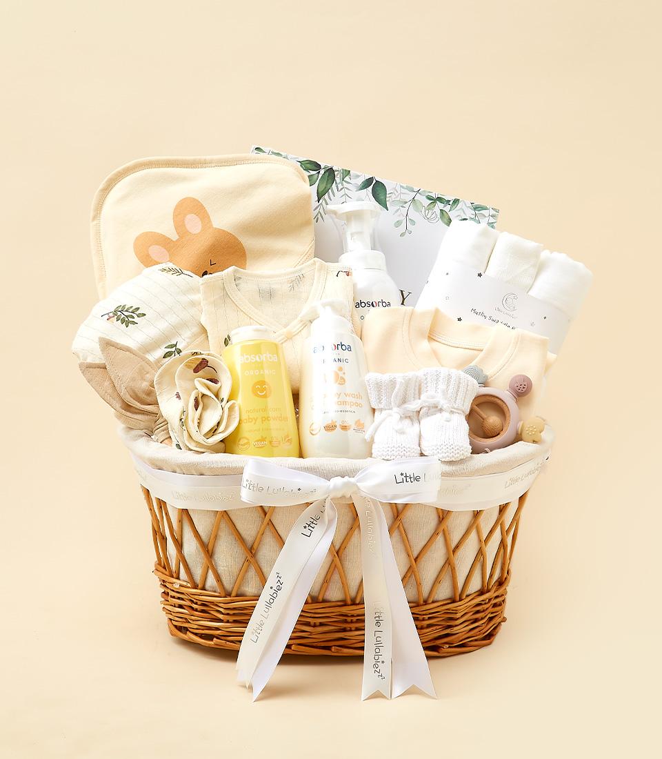Woven wicker newborn essentials hamper with cream bib, onesies, organic baby care, booties, and teether