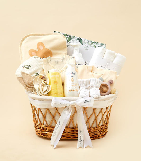 Woven wicker newborn essentials hamper with cream bib, onesies, organic baby care, booties, and teether