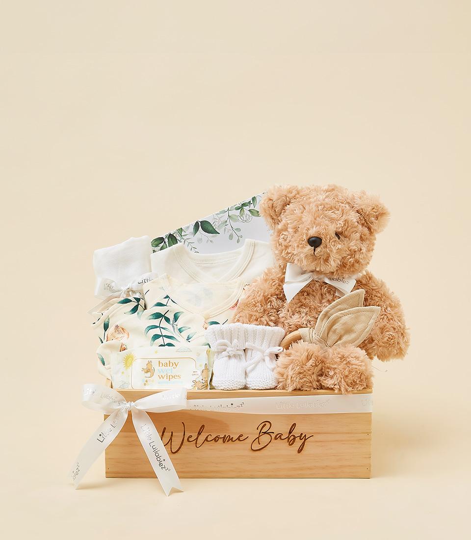 Welcome Baby gift set with cream onesies, teddy bear, wooden teether, and booties in wooden box