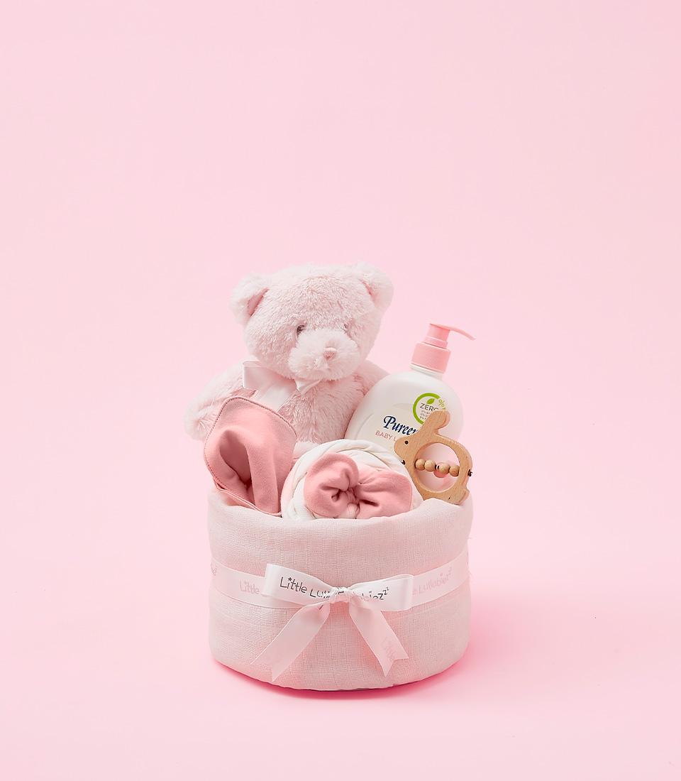 Pink newborn baby girl gift set with plush teddy, blanket, lotion, and wooden teether in luxury hamper