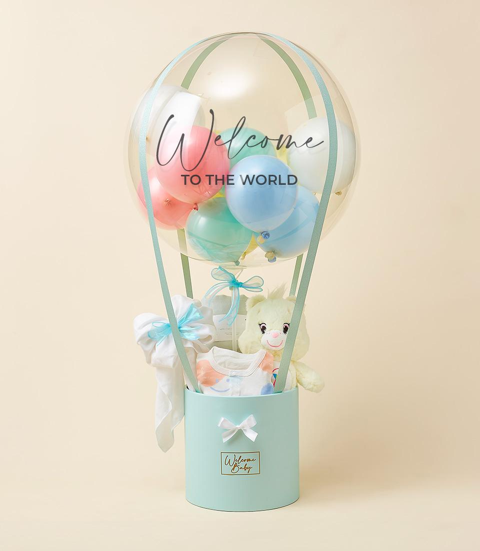 Pastel hot air balloon baby gift set with welcome message, light blue box, and soft toys for newborns