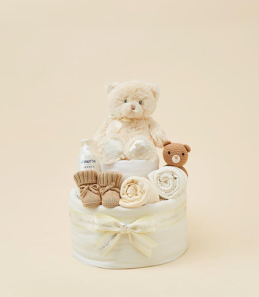 Cream plush teddy bear diaper cake gift set with yellow ribbons, organic baby products, and booties for newborns