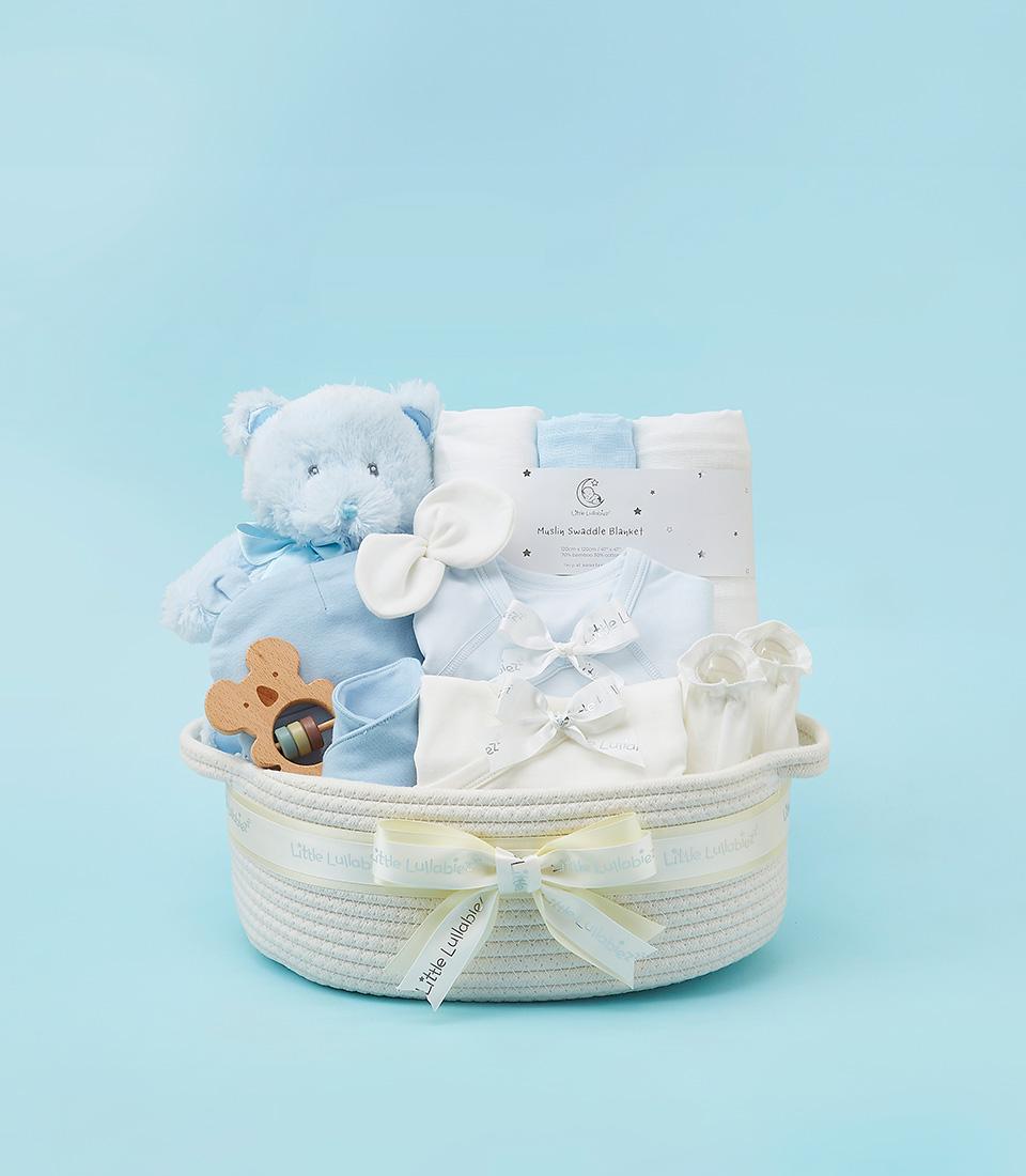 Luxury white rope baby gift basket with light blue teddy, rattle, booties, and muslin swaddle blanket for newborn boy