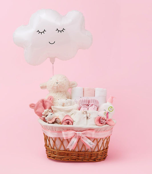 Cloud Nine Baby wicker gift basket with pink ribbon, filled with newborn essentials, clothing, and plush toys