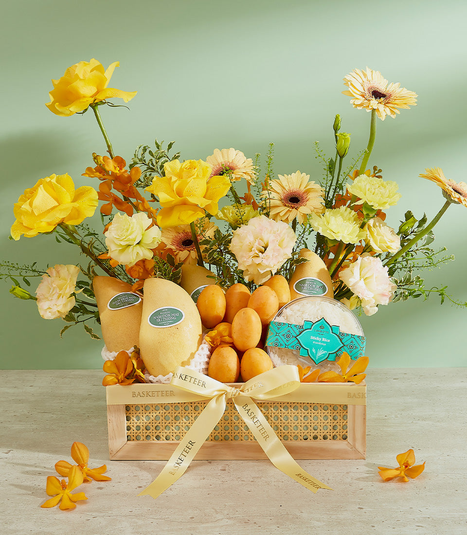 Nam Dok Mai mango gift basket with tropical fruits, sticky rice, and yellow roses in woven rattan with cream ribbon