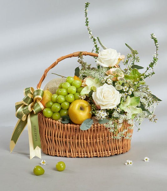 Premium green and white fruit basket with imported grapes, melon, pear, and fresh white roses