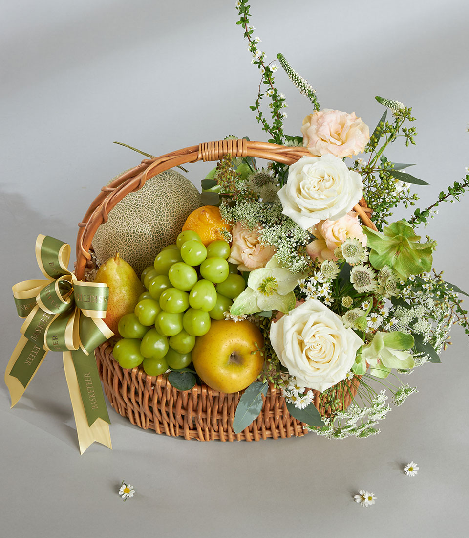 Premium green and white fruit basket with fresh imported cantaloupe, pears, grapes, and white roses