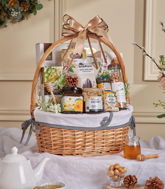 Wicker gift basket with organic honey, cocoa, jam jars, and gourmet wellness items tied with gold ribbon