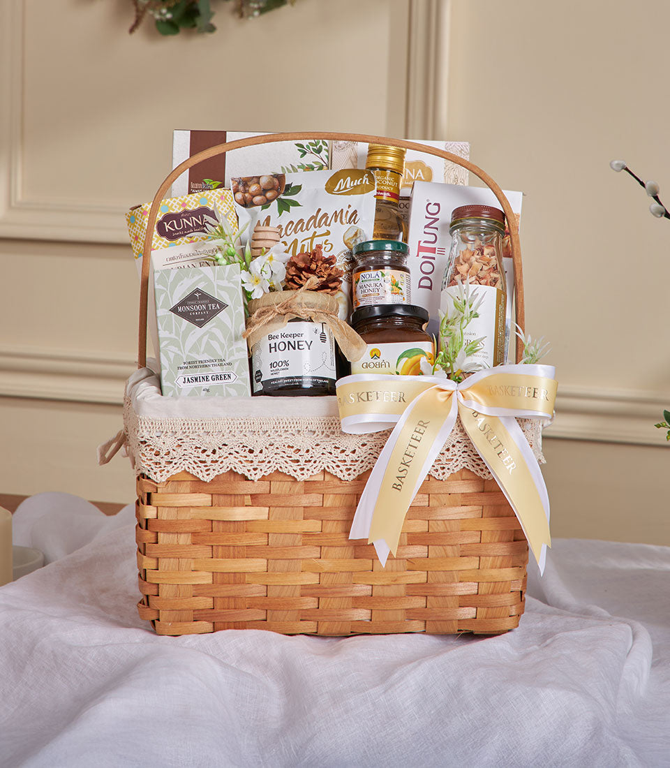 Organic Thai wellness gift basket with jasmine tea, raw honey, macadamia nuts, and dried fruit in woven wood